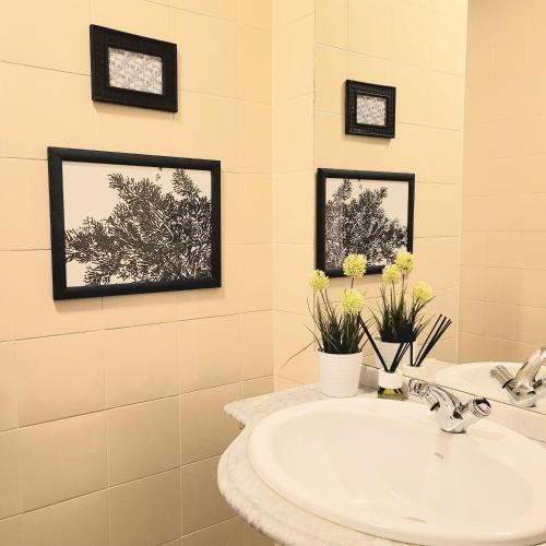 a bathroom with a sink and two pictures on the wall at HOSTEL Villanueva in Villanueva de Alcorón