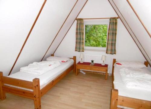2 Betten in einem Zimmer mit Fenster in der Unterkunft Ferienhaus am Twistesee in Bad Arolsen