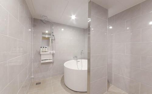 a white bathroom with a sink and a shower at H Avenue Hotel in Gyeongju in Gyeongju