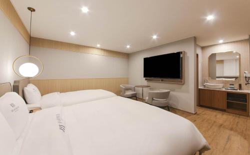 a hotel room with a large white bed and a bathroom at H Avenue Hotel in Gyeongju in Gyeongju