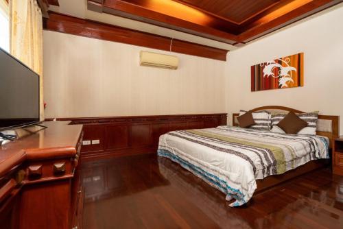 a bedroom with a bed and a desk with a television at Orchid Pool Villa Phuket - SHA Extra Plus in Phuket Town