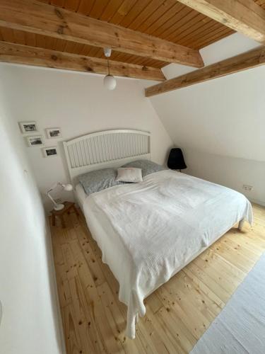 a bedroom with a white bed and a wooden floor at Fehrsland1 in Dollerup