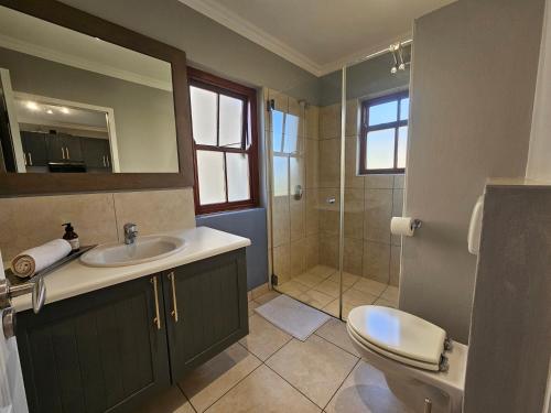 a bathroom with a sink and a toilet and a shower at Six Whale Rock Gardens with back up power for load shedding in Plettenberg Bay