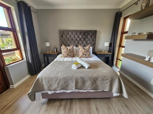 a bedroom with a large bed with two pillows at Six Whale Rock Gardens with back up power for load shedding in Plettenberg Bay
