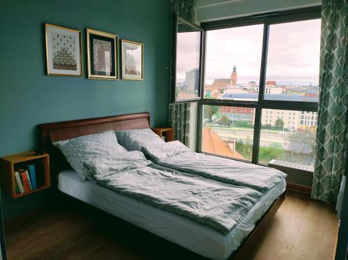 Bett in einem Zimmer mit einem großen Fenster in der Unterkunft M z widokiem in Breslau