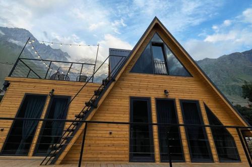 a house with a triangular roof with a balcony at Magic Hut_Kazbegi in Stepantsminda