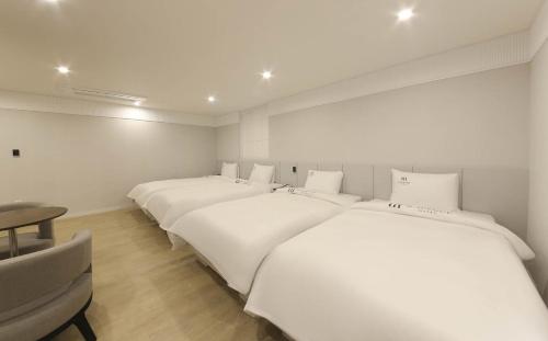 a row of white beds in a room at H Avenue Hotel in Gyeongju in Gyeongju