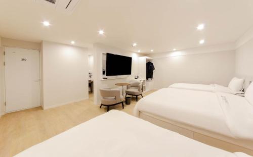 a white hotel room with two beds and a table at H Avenue Hotel in Gyeongju in Gyeongju