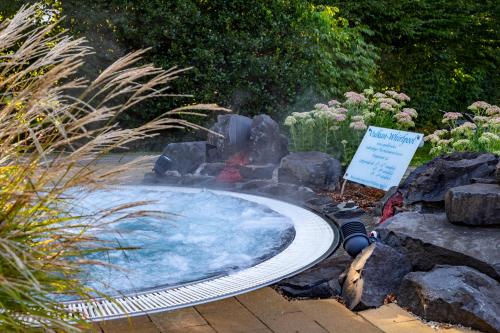 a hot tub in a garden with rocks and a sign at Hotel im Park in Bad Radkersburg
