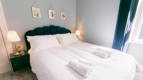 a bedroom with a large white bed with a blue headboard at Claremont in Llanfairfechan