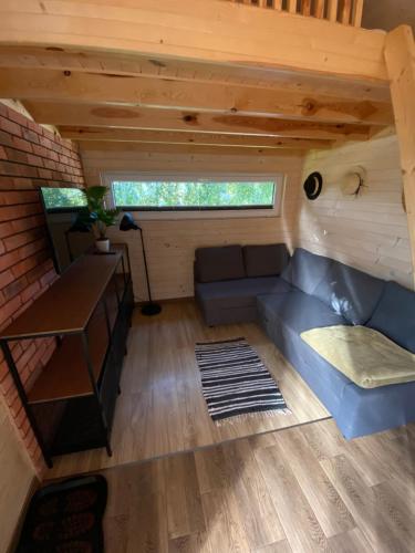 a living room with a couch in a tiny house at Domki u Łosia Bieszczady & Sauna in Polańczyk