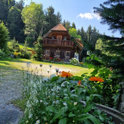 a log cabin with flowers in front of it at Moarhold Almhaus - Natur & Ruhe - Die Almhütte im Pöllauer Tal in Pöllau