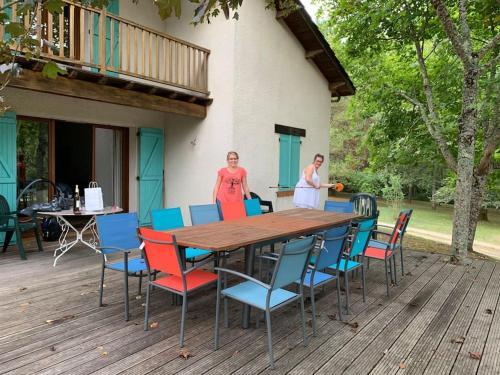 dos mujeres de pie en una terraza con una mesa y sillas en Grande maison avec parc de 6000m2, en Pompiey