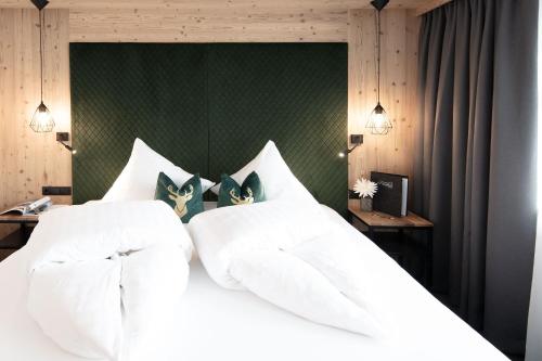 a bedroom with a white bed with a green headboard at Garni Rustica in Sölden