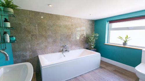 a bathroom with a white tub and a green wall at Cae Calch in Morfa Nefyn