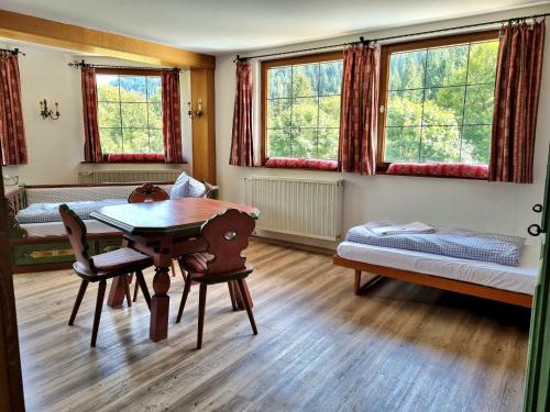 a room with a table and a bed and windows at Berghotel Almagmach in Immenstadt im Allgäu