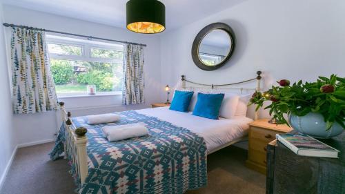 a bedroom with a bed with blue pillows and a mirror at Cae Calch in Morfa Nefyn