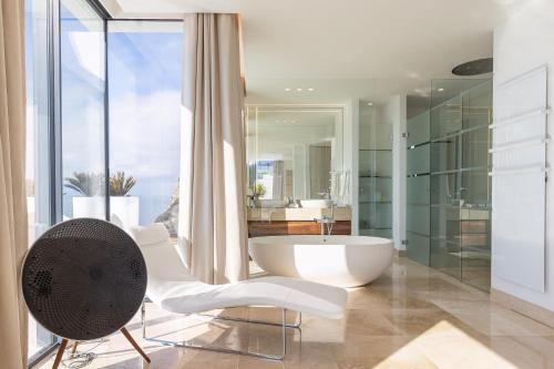 łazienka z wanną i krzesłem przed oknem w obiekcie Blue Sky Mallorca Luxury Villa w mieście Andratx