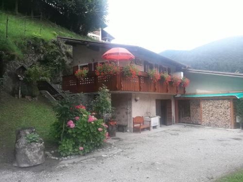 un bâtiment avec un balcon fleuri et un parasol dans l'établissement CASETTA INDIPENDENTE NEL VERDE PER 2/3 PERSONE, à Breguzzo