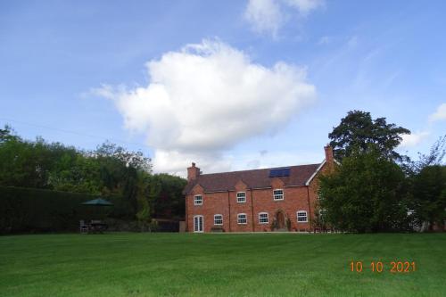 a large red brick house with a green lawn at The Old Coach House in Llangollen
