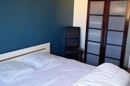 una camera con un letto bianco e una sedia nera di Appartement Rouen Ile Lacroix a Rouen