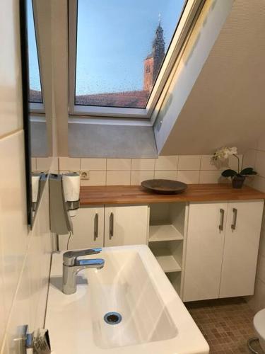 ein Bad mit einem Waschbecken und einem Fenster in der Unterkunft FeWo Wallblick Sonnenuntergang in Gardelegen