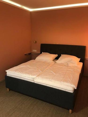 Schlafzimmer mit einem Bett mit weißer Bettwäsche und Kissen in der Unterkunft FeWo Wallblick Sonnenuntergang in Gardelegen