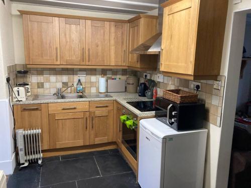 cocina con armarios de madera y nevera blanca en Bwthyn Heddwch - Peace Cottage, en Machynlleth
