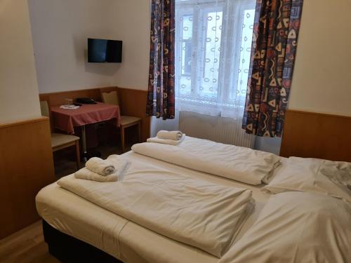 a bedroom with two beds and a table and a window at Pension Ani-Falstaff in Vienna