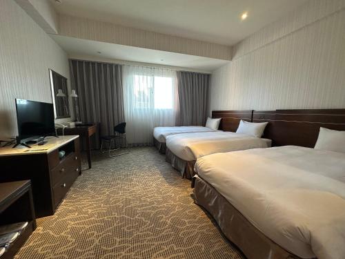 a hotel room with three beds and a television at Young Soarlan Hotel - Tainan in Tainan