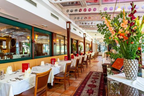 a restaurant with white tables and chairs and flowers at Hotel im Park in Bad Radkersburg