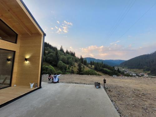 a couple of people sitting on the porch of a house at Cucu Zen Cazare Cabane Pensiuni Bucovina in Iacobeni