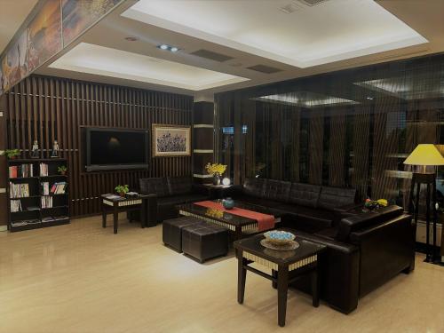 a living room with black leather furniture and a tv at Young Soarlan Hotel - Tainan in Tainan