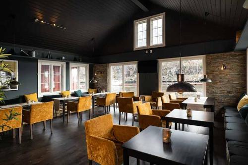 un comedor con mesas, sillas y ventanas en Tvedestrand Fjordhotell - Unike Hoteller en Tvedestrand