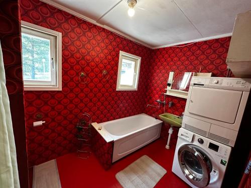 La salle de bains rouge est pourvue d'une baignoire et d'un lave-linge. dans l'établissement Bungalow Östavall Skogsvägen 20, à Haverö