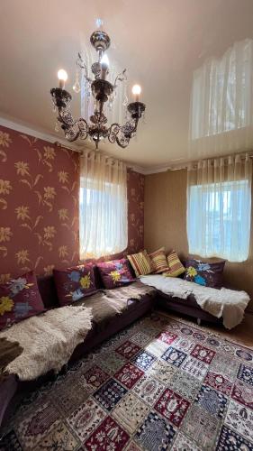 uma sala de estar com um sofá grande e um lustre em Mountain View Cozy House em Baytyk