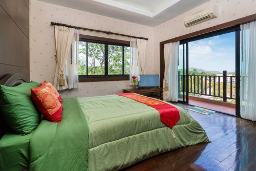 a bedroom with a green bed and a balcony at Orchid Pool Villa Phuket - SHA Extra Plus in Phuket Town