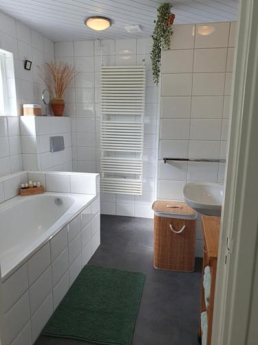 a white bathroom with a tub and a sink at Zonnig appartement Maasbommel. in Maasbommel