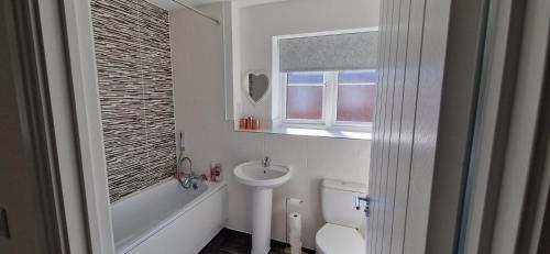 y baño con lavabo, aseo y espejo. en Brand new Entire 4-Bed House in Peterborough, en Peterborough