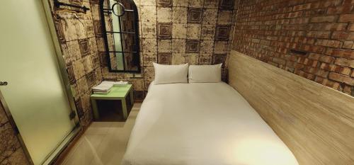 Ce lit se trouve dans une chambre dotée d'un mur en briques. dans l'établissement Cheers Loft Self Check-in Hotel, à Taipei
