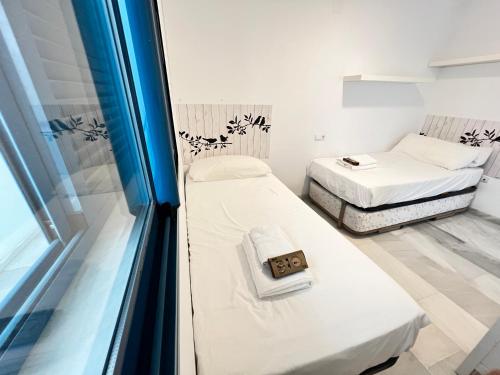 Duas camas num pequeno quarto com uma janela em PUSHE Castell de Ferro Beach & Tradition 2 em Castell de Ferro