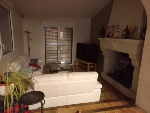 sala de estar con sofá blanco y chimenea en Le moulin neuf, en Saint-Nicolas-de-Bourgueil
