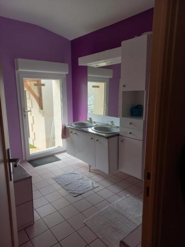 - une cuisine avec des murs violets et un évier dans l'établissement Le moulin neuf, à Saint-Nicolas-de-Bourgueil