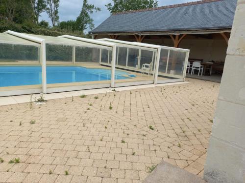 een huis met een zwembad met glazen wanden bij Le moulin neuf in Saint-Nicolas-de-Bourgueil