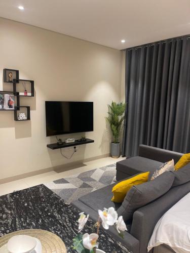 a living room with a couch and a flat screen tv at The Vibez Studio apartment - Jebel Sifah in Muscat