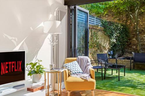 a living room with a chair and a tv at 3 Bedroom Mews Home - Clapham Common - Free Private Parking - Sleeps 5 - Newly Refurbished - Sweetpea & Pillow Properties in London