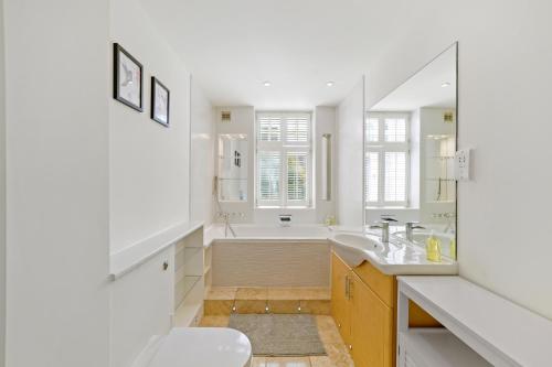 a white bathroom with a tub and a sink at 3 Bedroom Mews Home - Clapham Common - Free Private Parking - Sleeps 5 - Newly Refurbished - Sweetpea & Pillow Properties in London