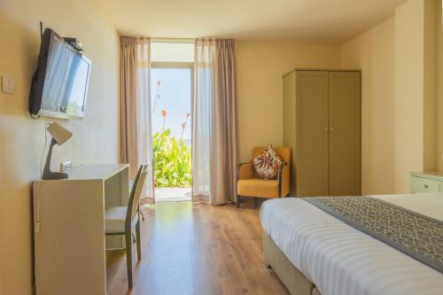 a hotel room with a bed and a desk and a television at Yehelim Boutique Hotel in Arad