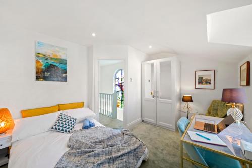 Schlafzimmer mit einem Bett und einem Schreibtisch mit einem Laptop in der Unterkunft 3 Bedroom Mews Home - Clapham Common - Free Private Parking - Sleeps 5 - Newly Refurbished - Sweetpea & Pillow Properties in London