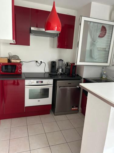 une cuisine avec des placards rouges et une lampe rouge dans l'établissement APPT MONTPELLIER 2 CHAMBRES et 10 minutes des Plages, à Montpellier